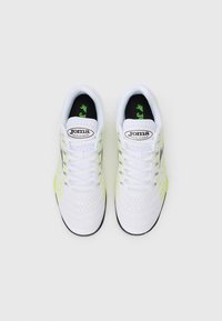Egy fehér Joma Maxima sportcipő pár neon sárga részletekkel és fekete talppal, felülnézetből, egyszínű háttéren.