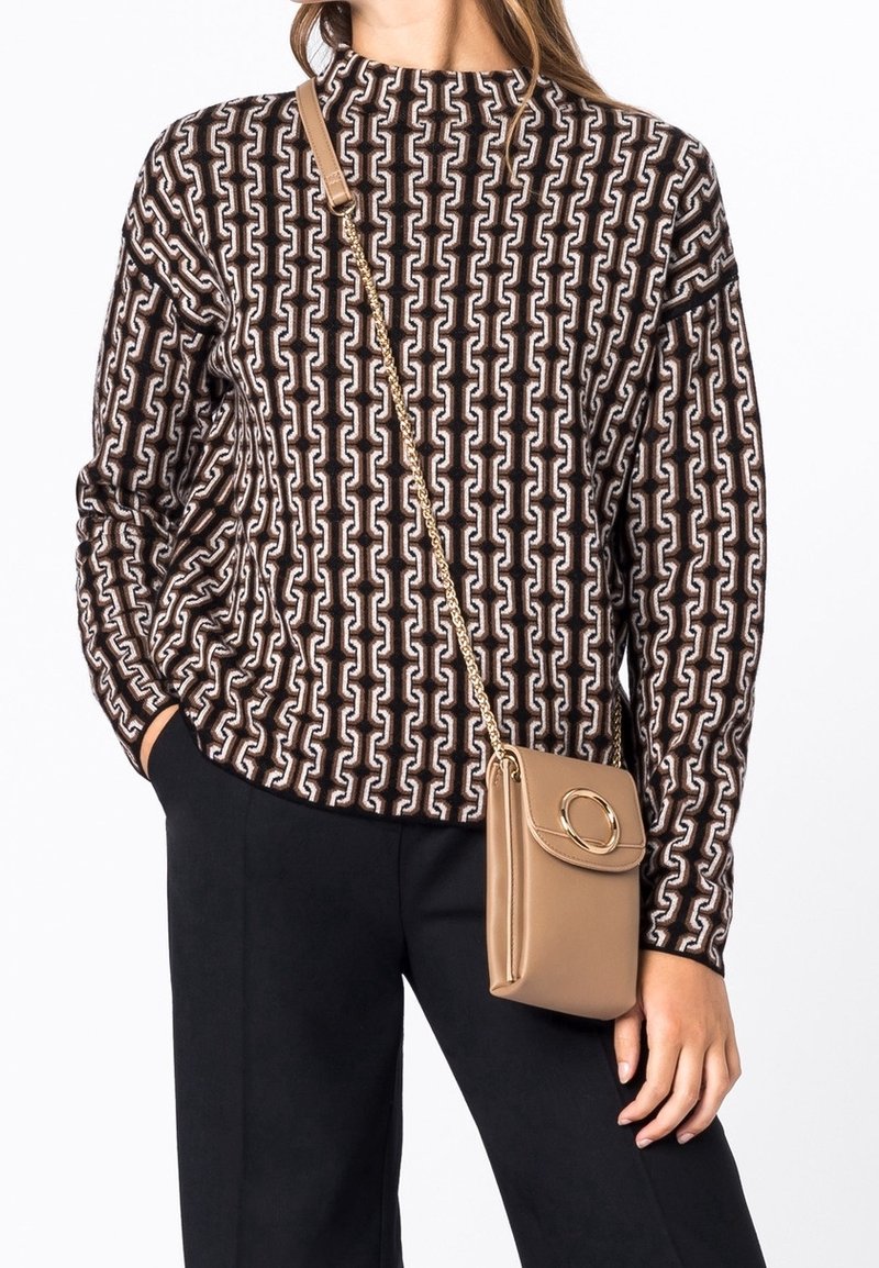 Brun og creme mønstrede sweater med høj hals; parret med en tan crossover taske med cirkulært element og guld kædeder.