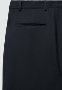 Pantaloni blu navy realizzati in un tessuto testurizzato, con una tasca posteriore singola dotata di un'apertura orizzontale stretta.