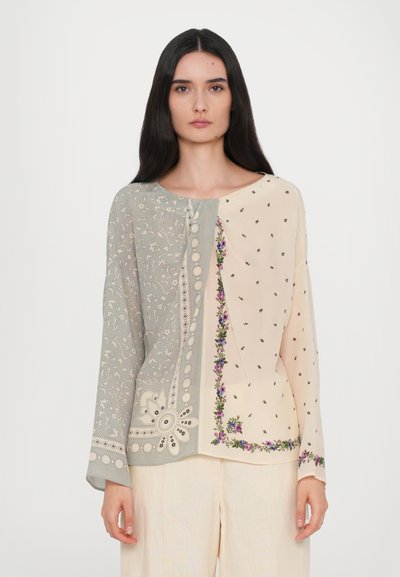 Long-sleeve blouse featuring a split design with gray and beige sections, intricate floral embroidery, polka dots, and decorative buttons.