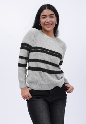 Hellgrauer Pullover mit schwarzen horizontalen Streifen, Rundhalsausschnitt und gerippten Bündchen. Kombiniert mit schwarzen Jeans im lässigen Schnitt.