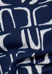 Nahaufnahme eines marineblauen Stoffs mit einem markanten weißen abstrakten geometrischen Muster, das gebogene und gerade Linien zeigt.