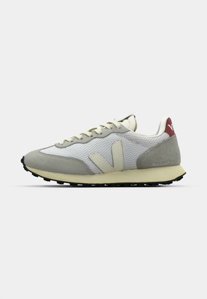 Light gray sneakers with mesh upper, suede accents, cream laces, and a black outsole. Features a red heel tab and embossed branding.