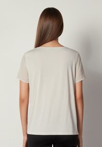 Ljust beige kortärmad t-shirt med rund halsringning, mjuk textur och avslappnad passform. Baksidan är heltäckande utan synliga mönster eller utsmyckningar.