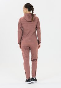 Lichtgewicht, flexibele twee-delige sportoutfit in gedempt roze. Inclusief een jas met capuchon en een gestructureerde achterkant, en ritsdetails op de broek.