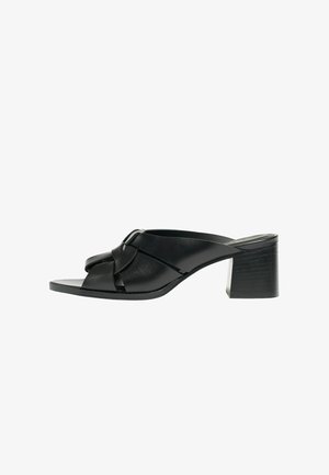 Sort mule med åben tå, knyttede læderstropper og blokhæl, vist fra siden på en hvid baggrund.