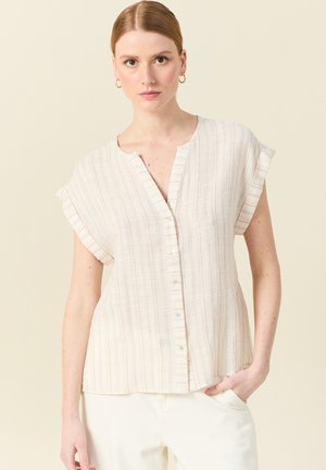 Blusa ligera de manga corta en beige con rayas verticales en tonos pastel, cierre de botones en el frontal y corte relajado. Textura de lino suave.