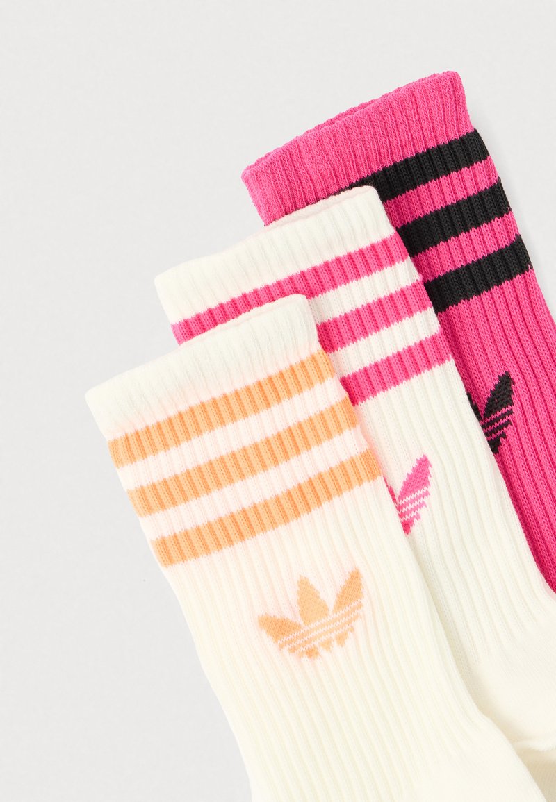 Tre paia di calzini a costine nei colori crema, rosa e nero con motivi a righe e piccoli dettagli con logo sui polsini. Tessuto con texture.