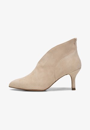 Botines de ante beige con punta puntiaguda y tacón bajo cónico. Presentan un diseño sin costuras y una textura suave.