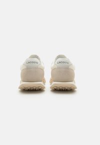 Lacoste tenisice s gornjim dijelom od bež antilopa i bijele kože, sa teksturiranim petnim dijelom, detaljem s logotipom i laganom gumenom potplatom.