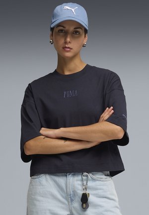 Mornarska skraćena majica s kratkim rukavima i izvezenim logotipom "PUMA". Nosila se uz svijetloplave traperice i plavu kapu s bijelim logotipom.