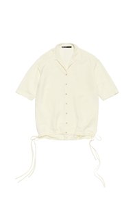 Camicetta a maniche corte in crema realizzata in tessuto leggero, con chiusura a bottoni fronte, orlo con coulisse e vestibilità comoda. Caratterizzata da un collo alla coreana.