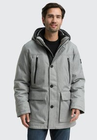 Grå polstret jakke med hætte, der har sorte lynlåslommer, trykknaplukninger og et tekstureret stof. Stilfuldt design med sidelommer.