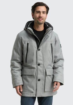 Veste grise rembourrée avec capuche, dotée de poches zippées noires, de fermetures à pression et d'un tissu texturé. Design élégant avec des poches latérales.