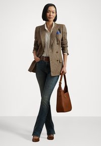 Brun houndstooth dobbelbrystet blazer, hvit skjorte, blå lommetørkle, mørke jeans, brun lærbelte og brun håndveske.