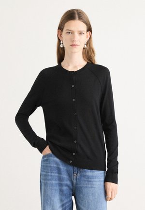 Svart cardigan med rund hals, lange ermer og knaplukking. Laget av et mykt materiale, med en løsning passform og ribbede mansjetter.