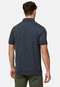 Marineblå kortærmet polo t-shirt med tekstureret stof og krave. Har en lige kant og et diskret logo på den nederste side.