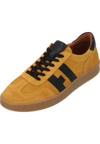 Sneakers in suede giallo con accenti neri, caratterizzati da una punta tonda, lacci neri e suola in gomma. Dettagli di cucitura notevoli lungo la tomaia.