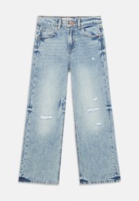 Jeans de mezclilla azul claro con un corte holgado. Presentan parches desgastados, dobladillos deshilachados y un diseño clásico de cinco bolsillos con herrajes de cobre.