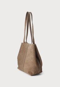 Bruine suède schoudertas met twee verlengde handvatten, een zachte textuur en een gestructureerde vorm. Bevat zichtbare stiksels en naaddetails.