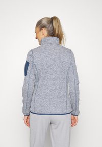 Fleecejack met een hoge kraag, gestructureerde grijze stof, blauwe accenten en een getailleerd silhouet. Lange mouwen en ribgebreide onderrand.