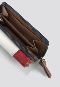 Portafoglio con zip caratterizzato da sezioni in pelle bianca, rossa e blu navy. Interno marrone con scomparti per carte e attacco per portachiavi. Texture morbida.