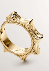 Anillo de oro con una superficie texturizada, que presenta un diseño único en forma de estrella y acentos de perlas a lo largo de los bordes. Acabado interior liso.