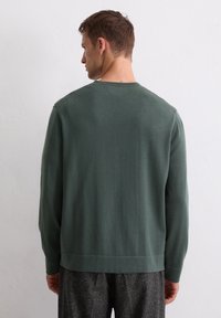 Dunkelgrüner Pullover mit langen Ärmeln, Rundhalsausschnitt und strukturiertem Finish. Er verfügt über eine einfarbige Gestaltung und einen lässigen Schnitt am Saum.