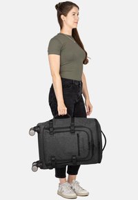 Schwarze Rolltasche mit strukturierter Oberfläche, robusten Griffen, Rollen und Schnallen; verfügt über eine vordere Reißverschlusstasche für einfachen Zugriff.