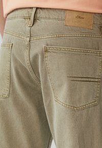 Beżowe dżinsy o teksturowanym wykończeniu, z dwiema tylnymi kieszeniami, przeszyciami oraz skórzaną metką s.Oliver przy pasku.