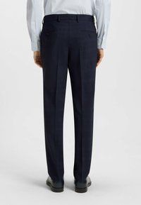 Marinblå rutiga byxor med en skräddarsydd passform, med två bakfickor och subtila randiga detaljer. Materialet verkar mjukt med en lätt textur.