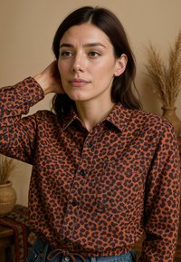 Bruine panterprint shirt met knopen, kraag en een borstzak. Heeft een relaxte pasvorm en een gestructureerde stof. G gedragen met blauwe jeans.