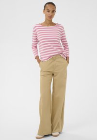 Svītrains rozā un baltas krāsas garām piedurknēm tops ar apaļu kakla izgriezumu, kombinēts ar vaļīgām khaki krāsas biksēm. Bikšu audums ir mīksts, ar platu kāju.