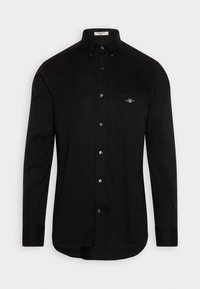 Chemise noire à manches longues avec boutons, col et poche poitrine avec un petit logo brodé sur le côté gauche de la poche.