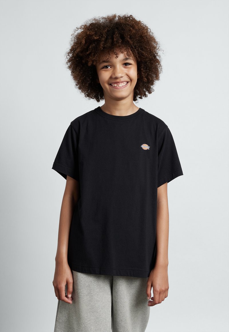 Svart bomulls t-shirt med korta ärmar, rund hals och liten logga på bröstet, tillsammans med ljusgrå shorts. Slät textur.