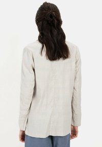 Lichtbeige lange mouw shirt met een rechte snit, subtiele textuur en een schoon rugnaadontwerp. Heeft geen zichtbare hardware of accenten.