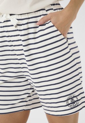 Gestreifte Shorts im Weiß und Marineblau Design. Hergestellt aus weichem Stoff mit elastischem Bund, ausgestattet mit Taschen und einem Logo-Patch.