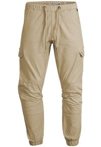 Pantalons cargo beige clair avec taille élastique, cordon de serrage, poches latérales à rabat, coutures au niveau des genoux et poignets élastiques.