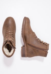 Brown faux leather ankle boots with lace-up front, side zipper, rounded toe, and textured rubber sole. Soft lining visible at the top.