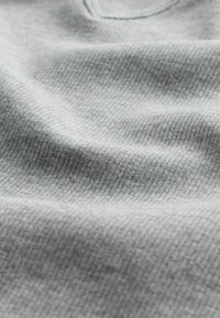 Tessuto grigio chiaro con trama testurizzata e motivo a coste, caratterizzato da una superficie liscia e un design a v.