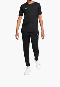 Camiseta y pantalones deportivos negros de Nike, fabricados en un tejido suave y transpirable; cuentan con un logo blanco en el lado izquierdo del pecho y el muslo, con un diseño ajustado.