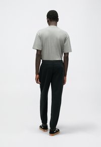 Szary t-shirt z krótkim rękawem, czarne dresy z elastycznym pasem i czarne trampki z białymi akcentami. Wytrzymały materiał i luźny krój.