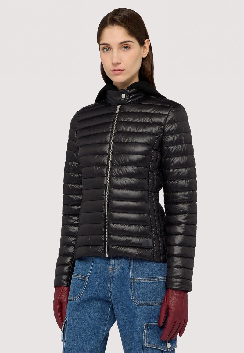 Černá péřová bunda s vodorovným prošíváním a vysokým límcem, se zapínáním na přední zip. Model má na sobě burgundské kožené rukavice.