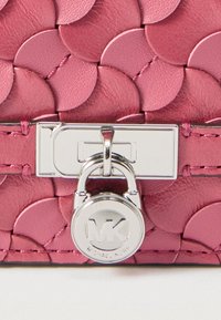 Pink leather handbag with overlapping circular scales and silver lock detail featuring MK logo.