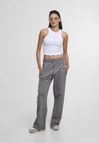 White ribbed crop top with round neckline; gray loose-fitting sweatpants with an elastic waistband and side pockets; light gray sneakers.