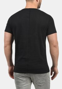 Svart t-skjorte med kort erme laget av bomull. Har et enkelt design med en rett bakseam og en klassisk passform.