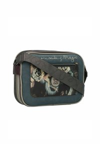 Bolso bandolera en verde azulado con materiales de texturas mixtas, bolsillo frontal decorativo con un patrón floral y correa ajustable con texto impreso.