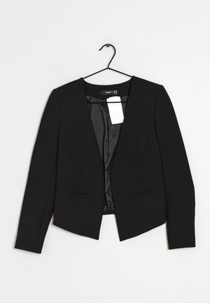 Blazer noir ajusté à manches longues et devant ouvert, suspendu sur un cintre noir sur un fond blanc uni.