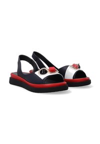 Marineblauwe sandalen met een rode zool, voorzien van een witte accent en decoratieve hardware in zwart en rood. Open-toe ontwerp met een slingback stijl.