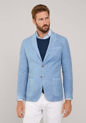 Lichtblauwe linnen blazer met drie knopen, gestikte revers en twee voorzakken. Draag het over een marineblauwe trui en witte broek.